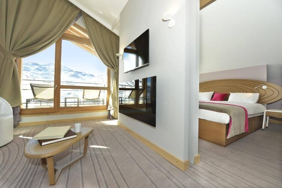 Primary bedroom with king bed and snow-capped mountain views through floor-to-ceiling windows