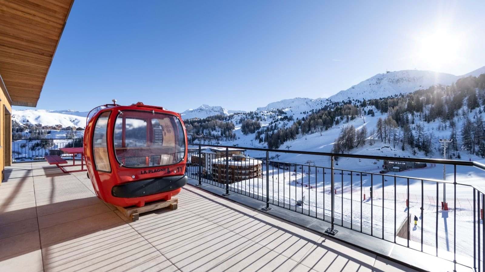 Private balcony with red gondola seating overlooking La Plagne ski slopes