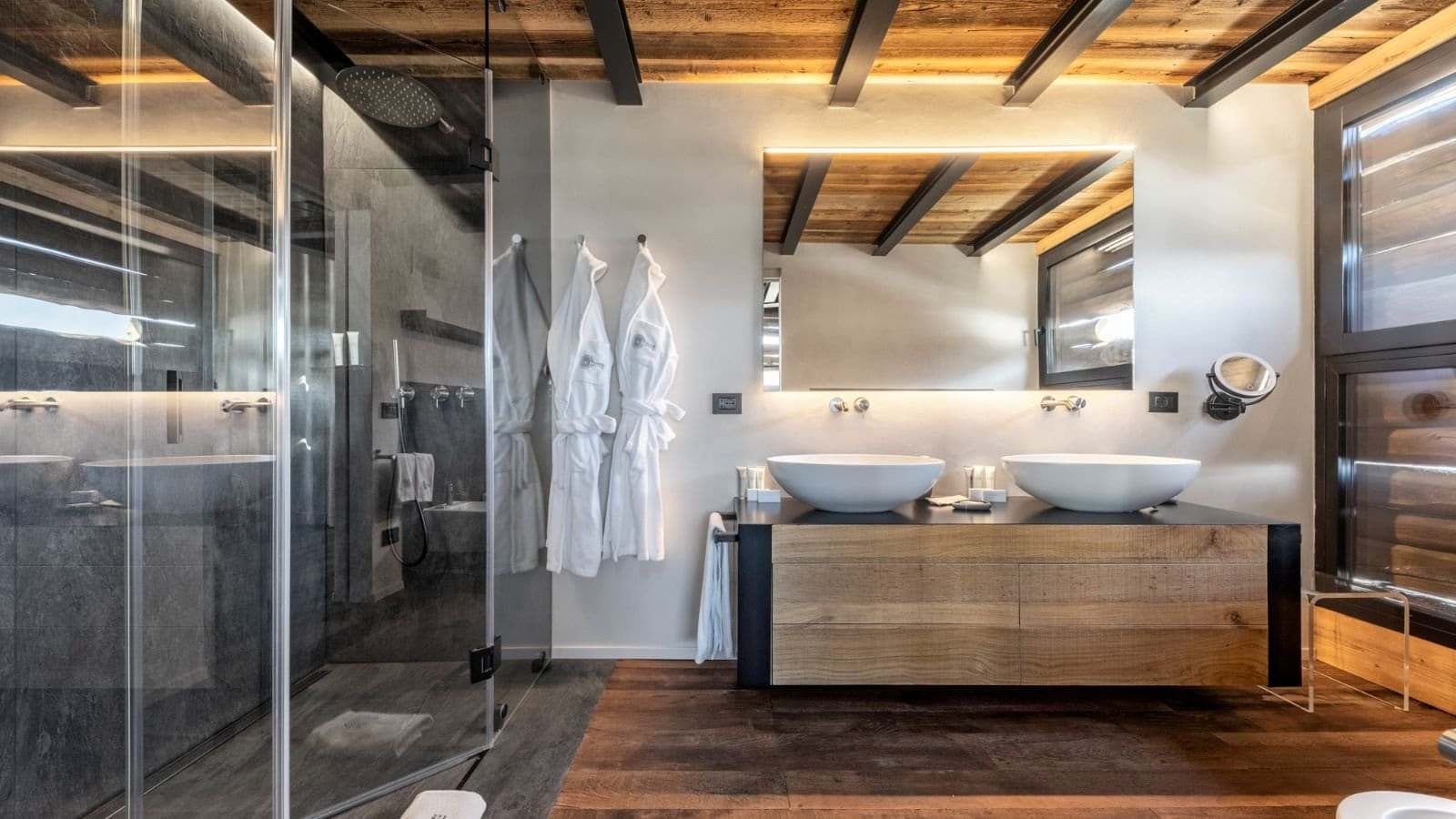 Bathroom with dual vessel sinks, walk-in rainfall shower, and backlit mirror