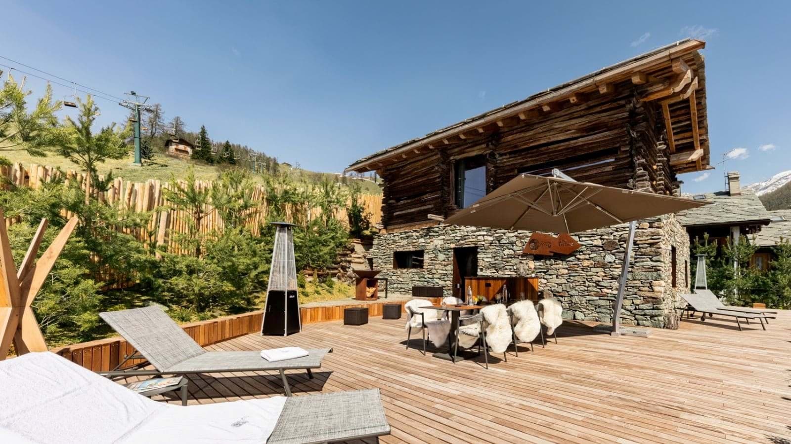 Stone-clad terrace with outdoor dining, heater, and views of ski lifts