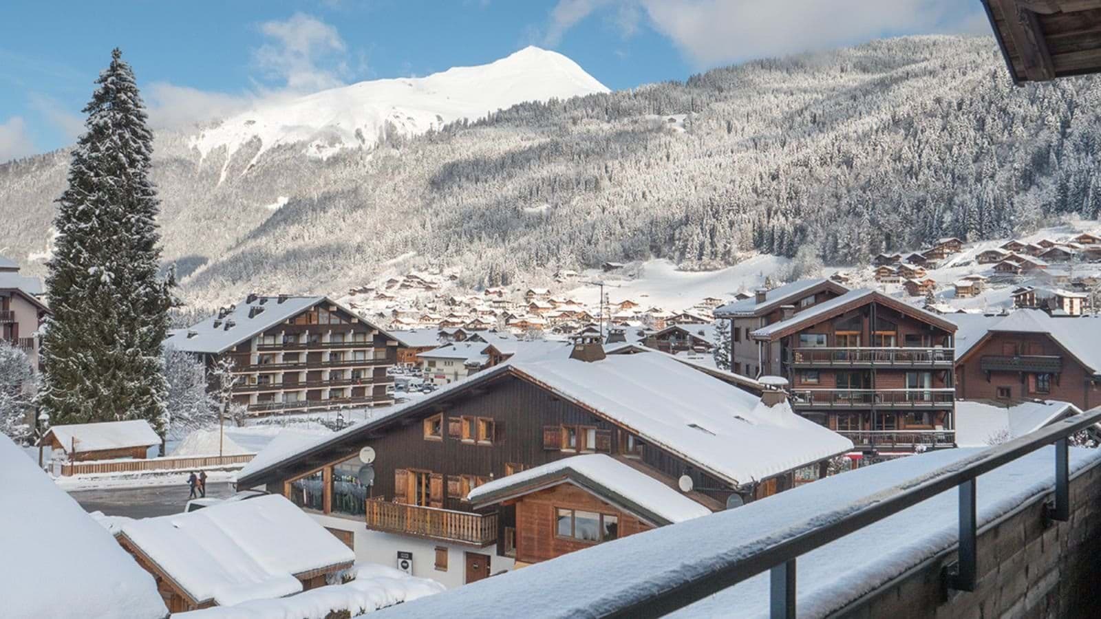 Private balcony view overlooking snow-covered village and Alpine peaks