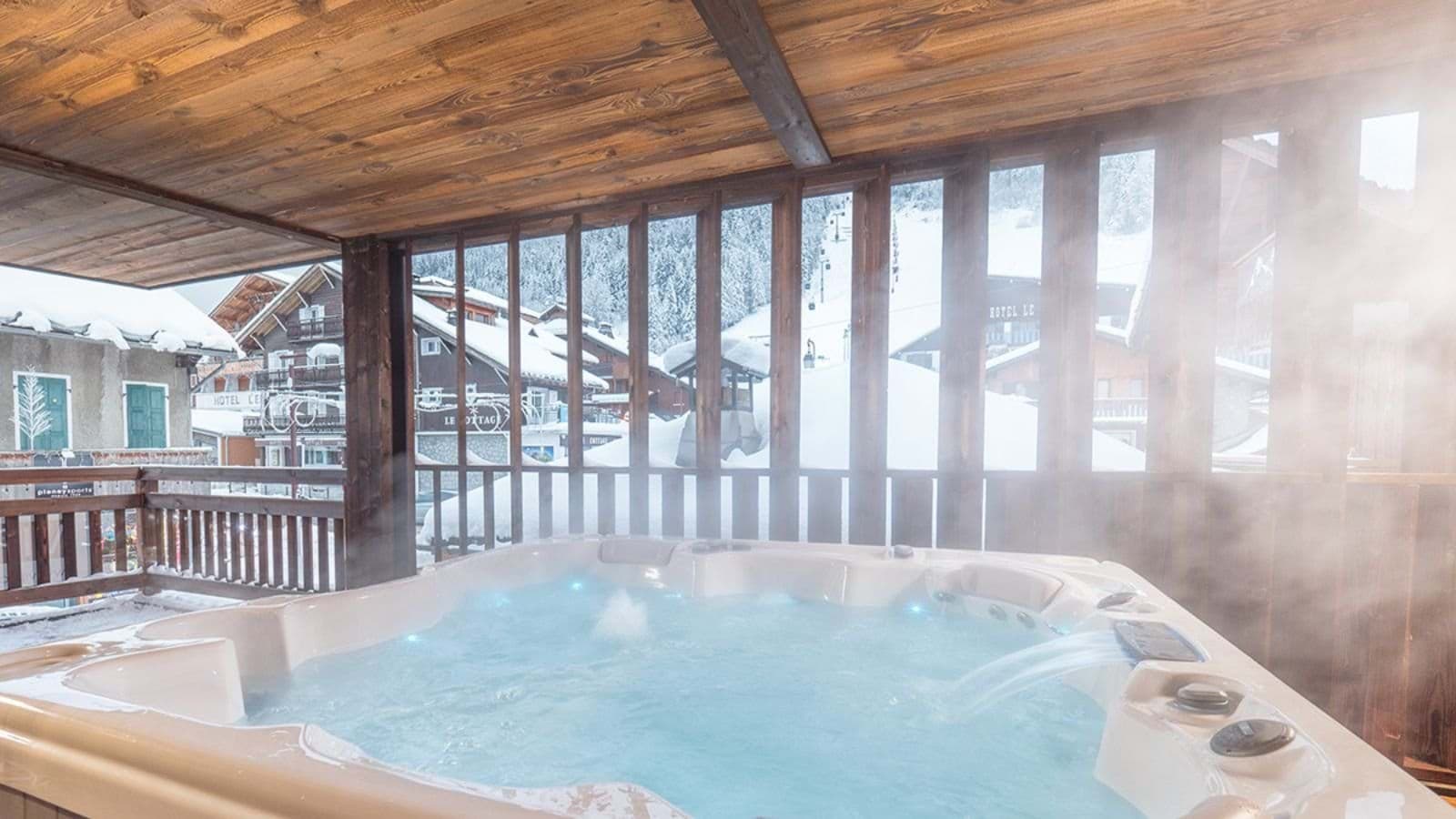 Covered outdoor hot tub overlooking the village and ski slopes