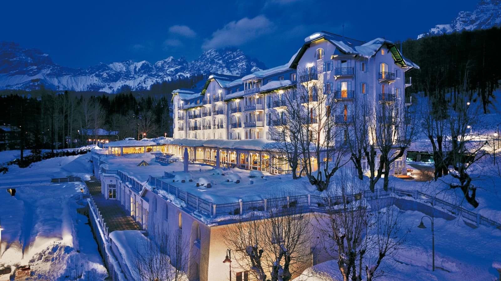 Hotel exterior at dusk with Dolomite mountain views and private balconies
