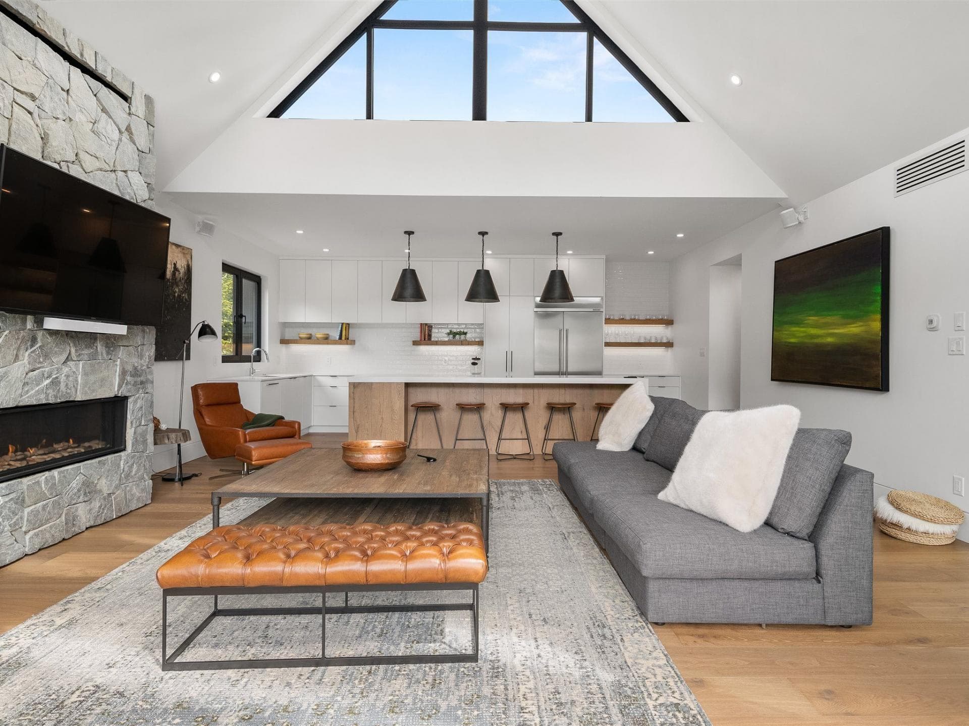 Open-concept living area with stone fireplace and kitchen island seating for 4