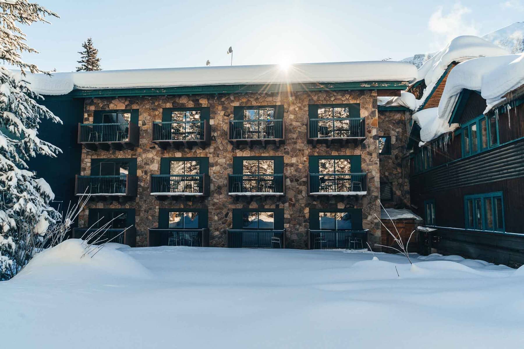 Stone lodge exterior with private balconies overlooking the snow-covered grounds
