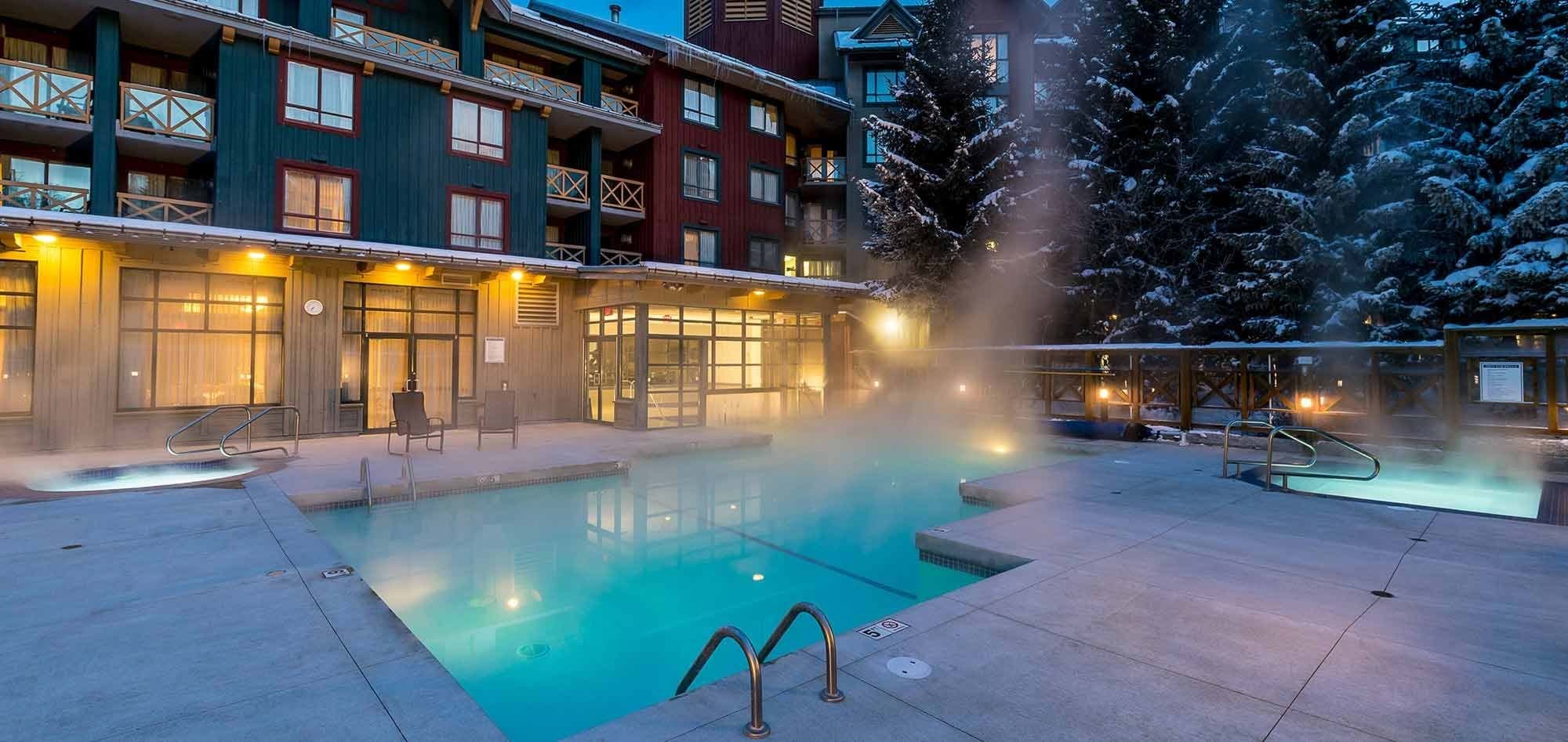 Heated outdoor pool and two hot tubs with snowy mountain backdrop