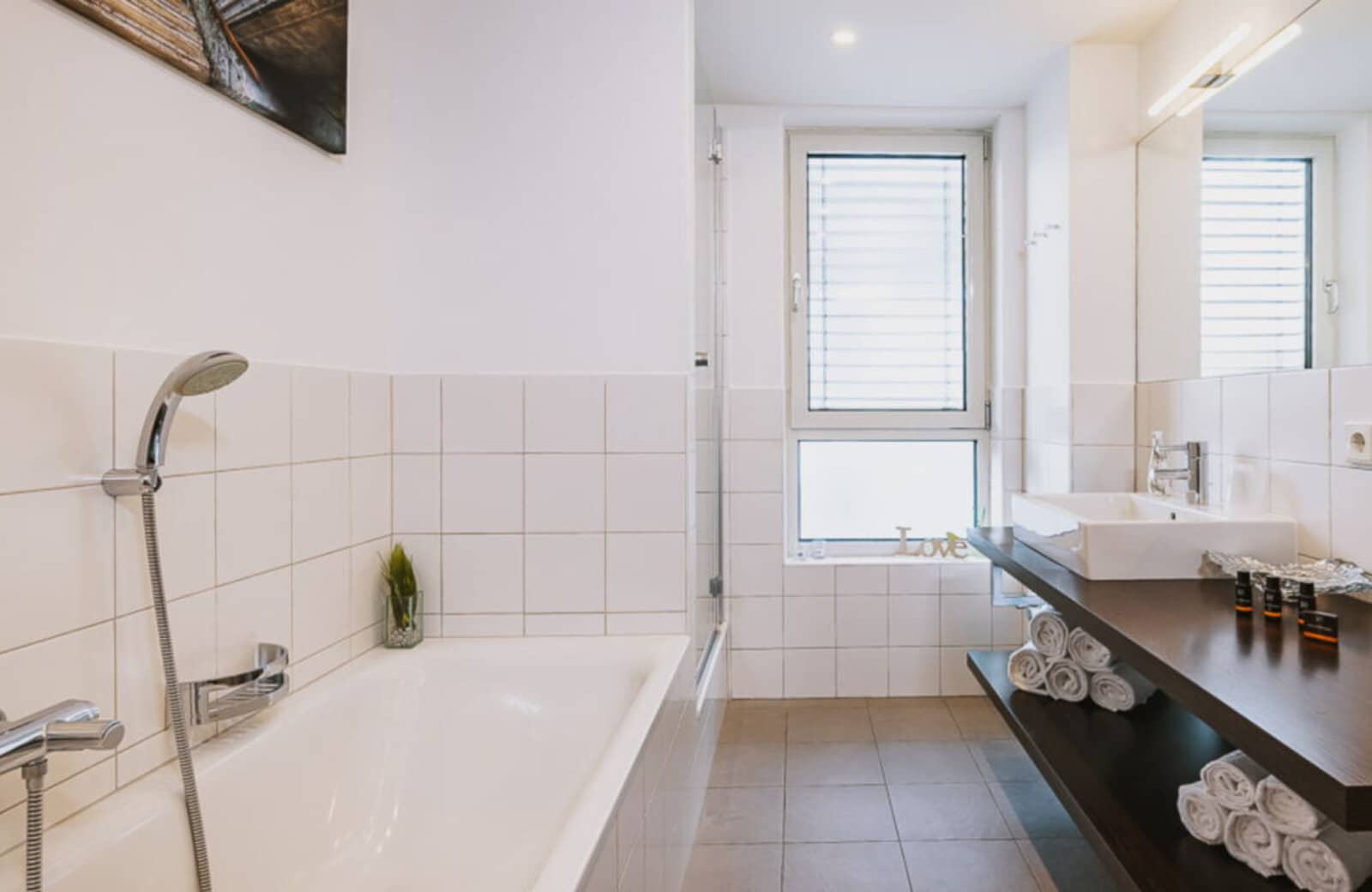 Bathroom with soaking tub, handheld shower head, and floating vanity