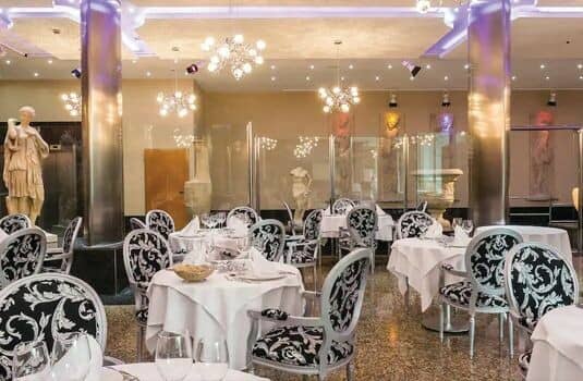 Formal dining room with marble flooring and classical statues