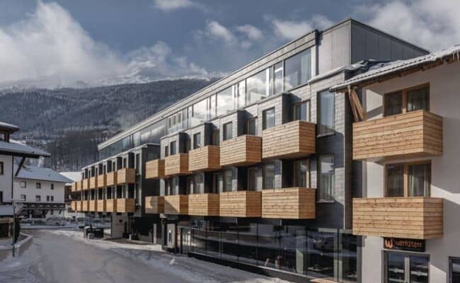 Building exterior with private wood-slat balconies and mountain views