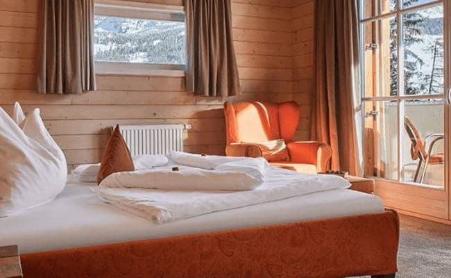 Wood-paneled bedroom with balcony access and mountain views