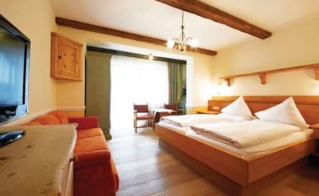 Guest suite with twin-configured king bed, sofa, and exposed timber beams