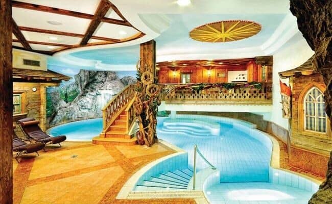Indoor pool with grotto mural, loungers, and mezzanine balcony level