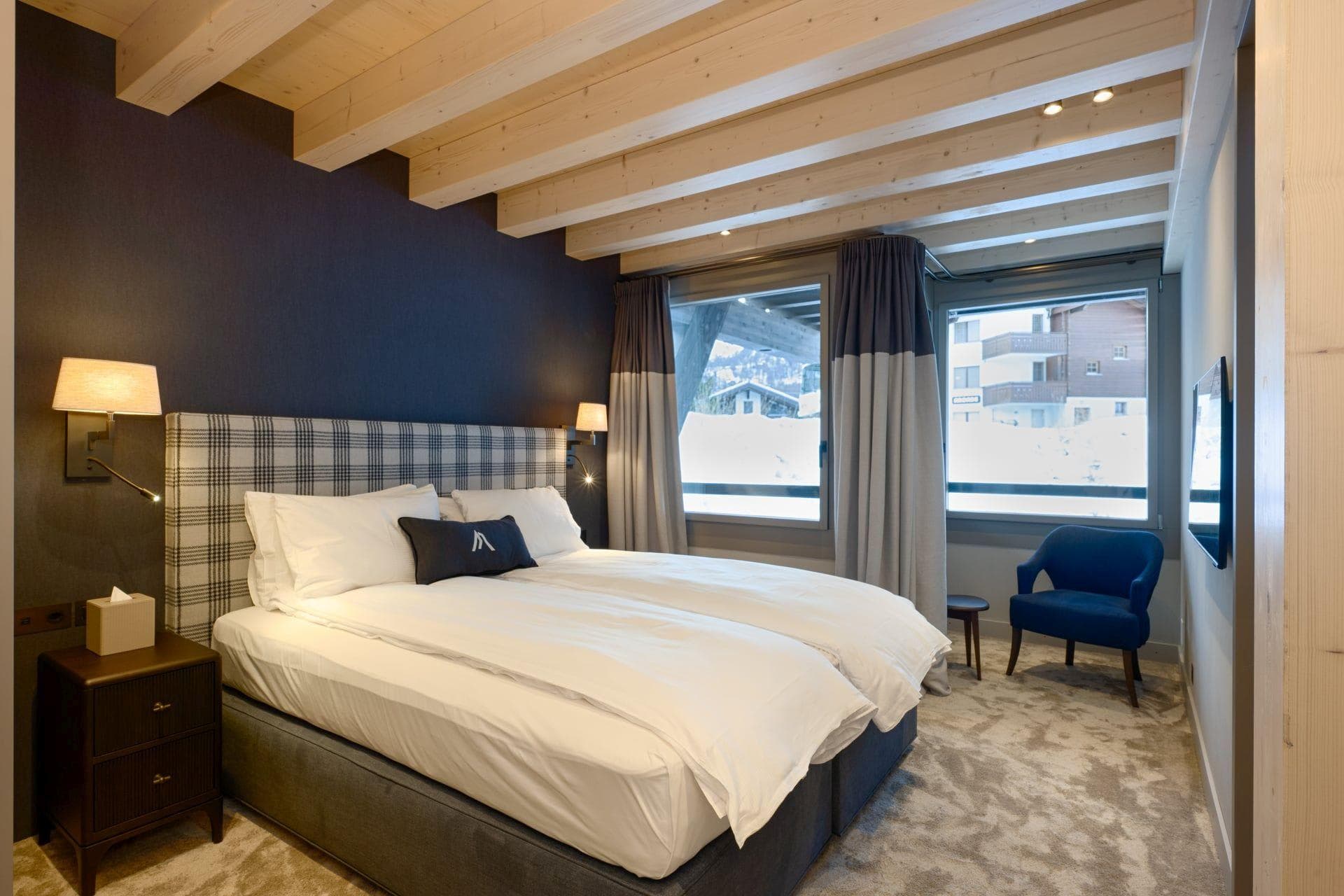 Bedroom with zip-and-link twin beds, wall-mounted reading lights, and snowy village views