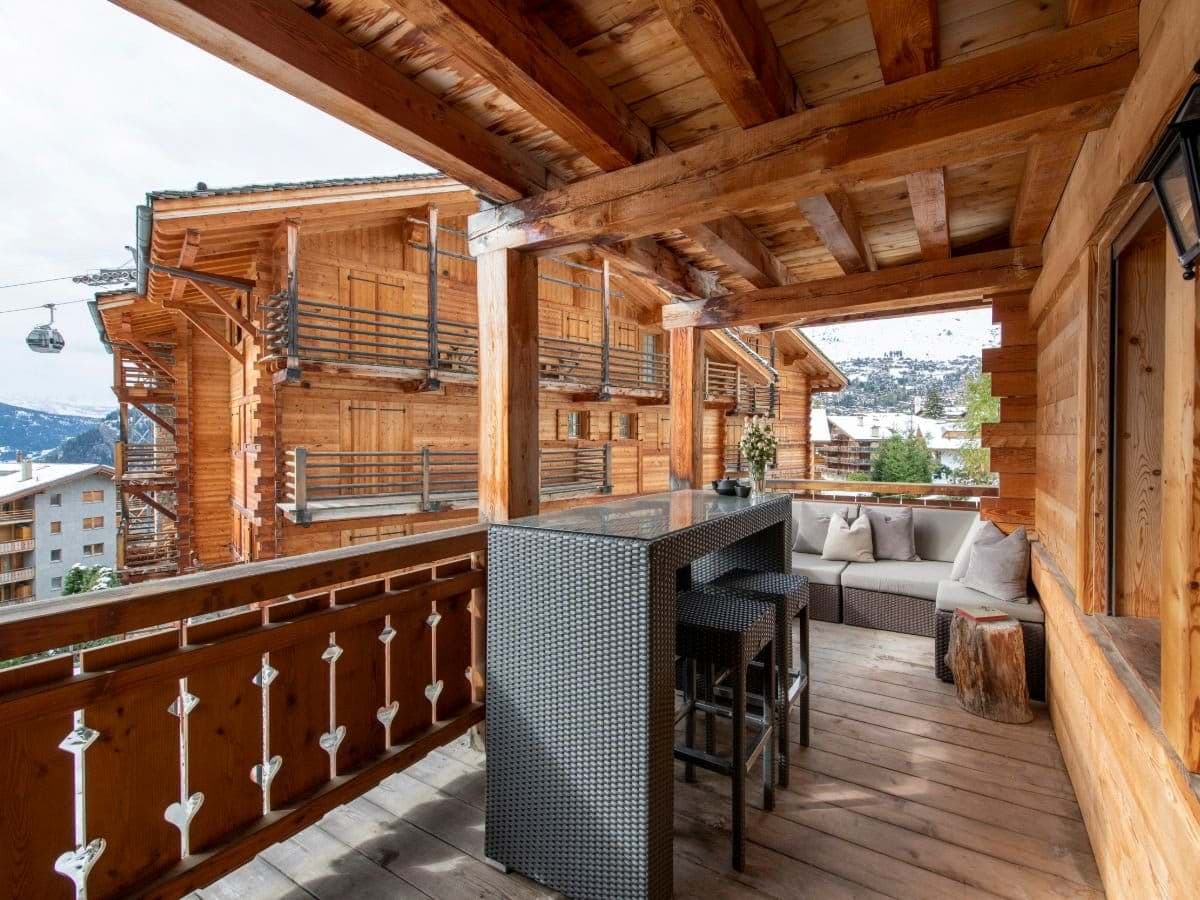 Covered balcony with sofa and high-top seating near ski gondola
