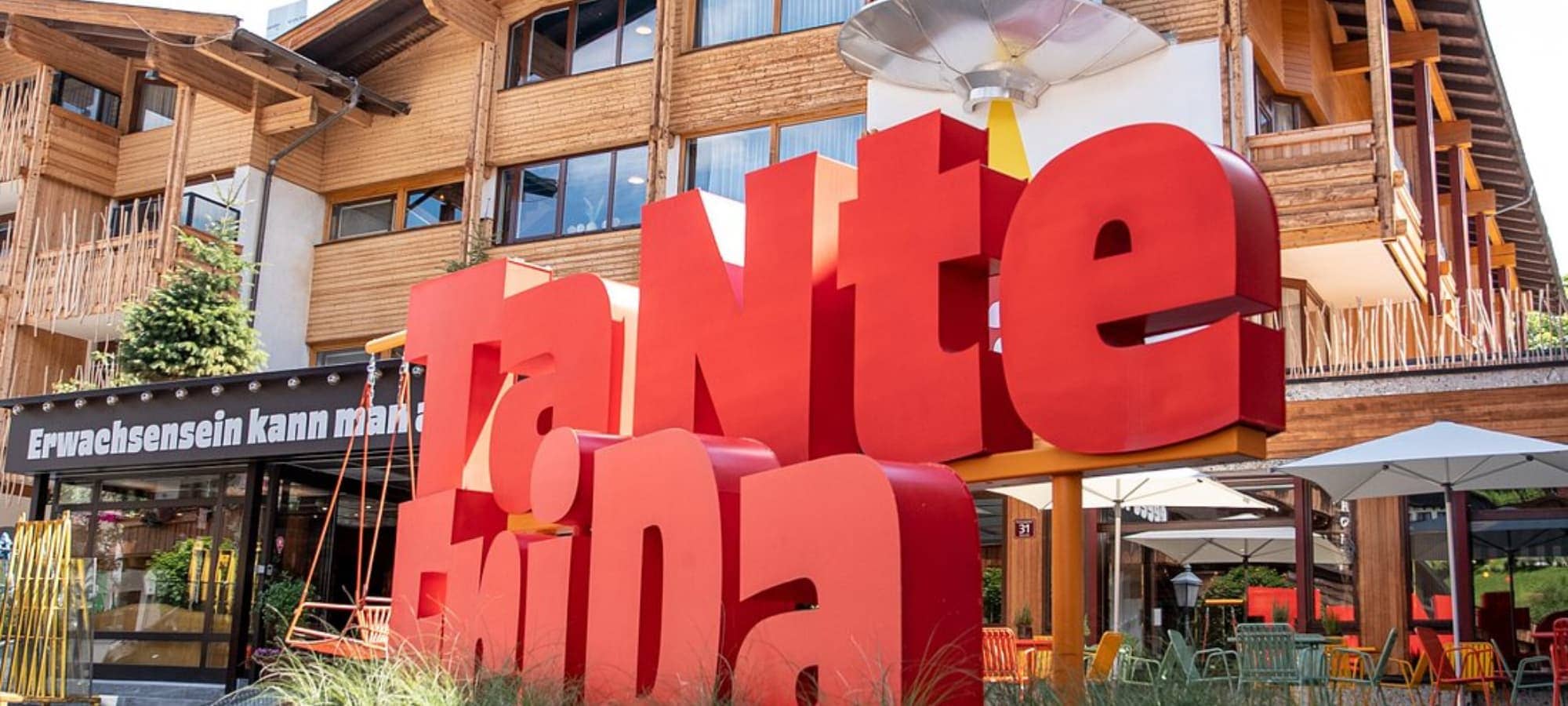 Hotel exterior featuring outdoor patio seating and signature red signage