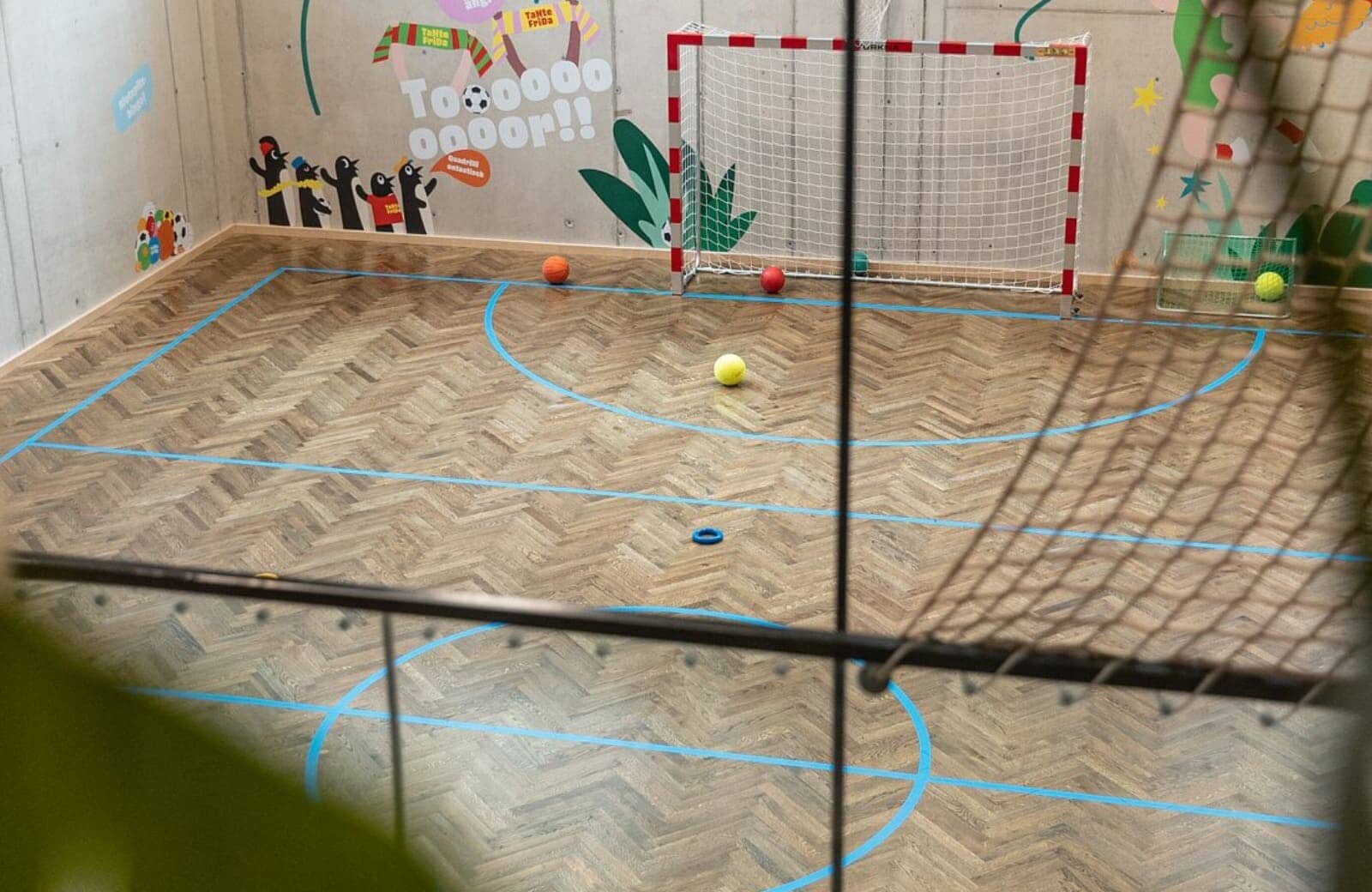Indoor sports court with mini soccer goal and parquet flooring