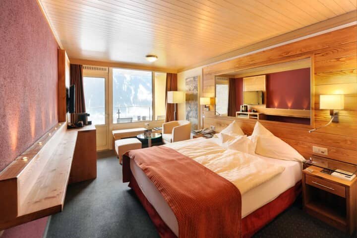 Guest bedroom with king bed, mountain-view balcony, and wood-paneled walls