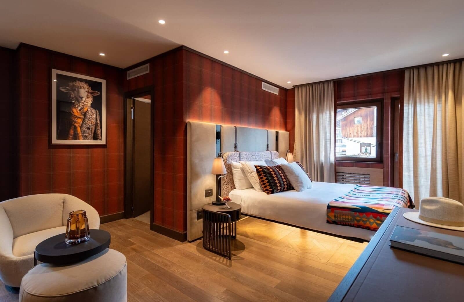 Guest bedroom with king bed, tartan wallpaper, and armchair seating