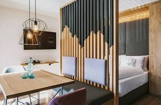 Studio layout with slat partition separating dining area and queen bed