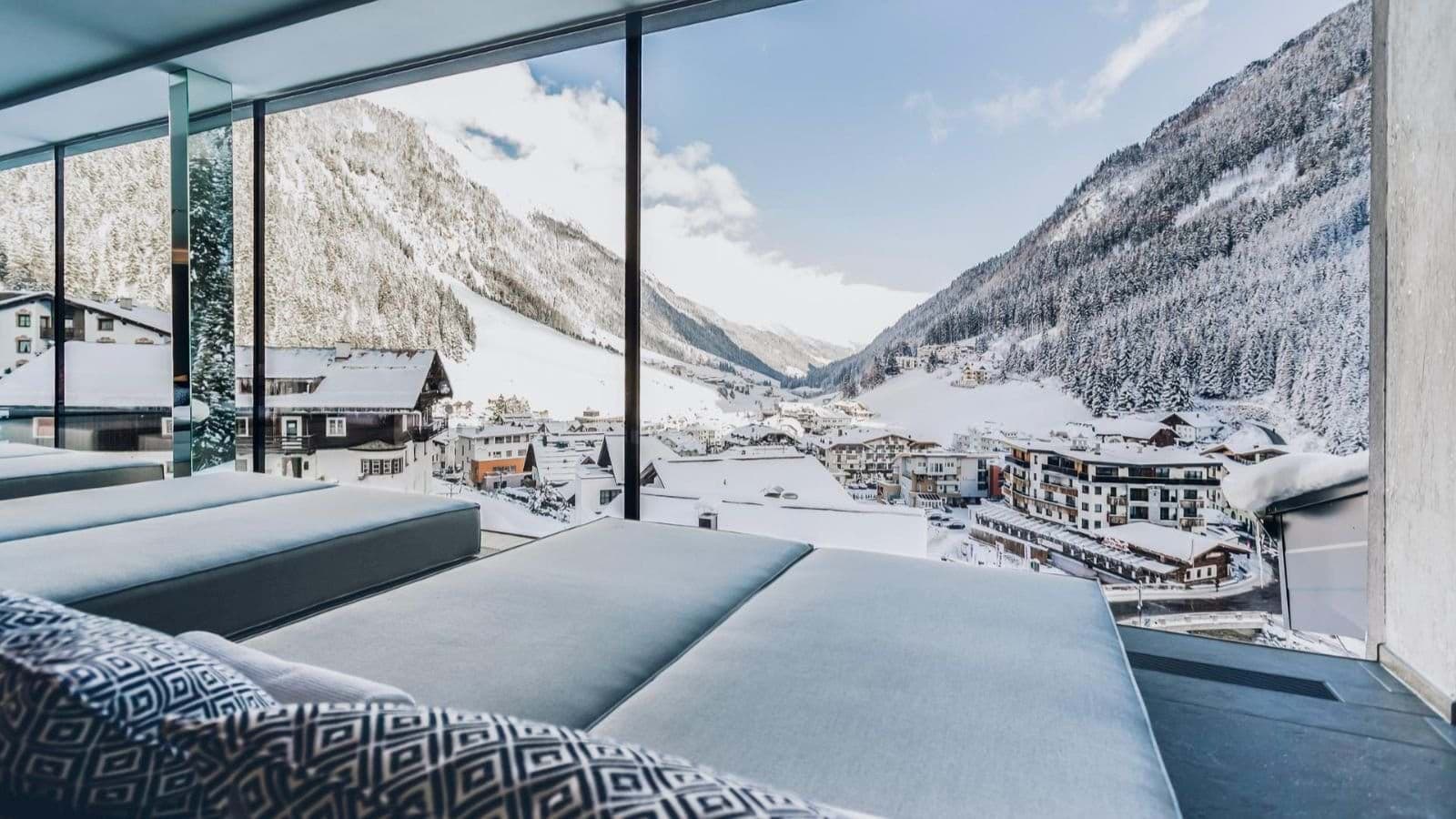 Relaxation area with daybeds and floor-to-ceiling alpine village views