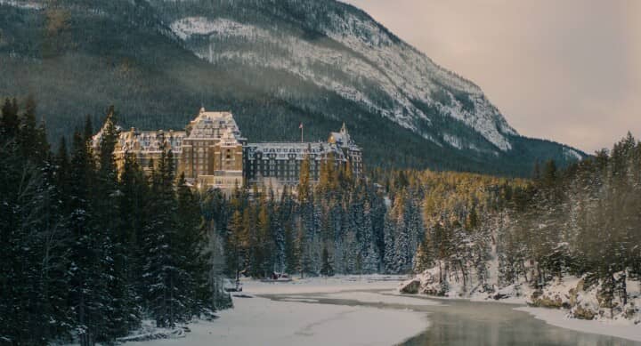 Chateau-style resort overlooking snow-covered forest and frozen river valley