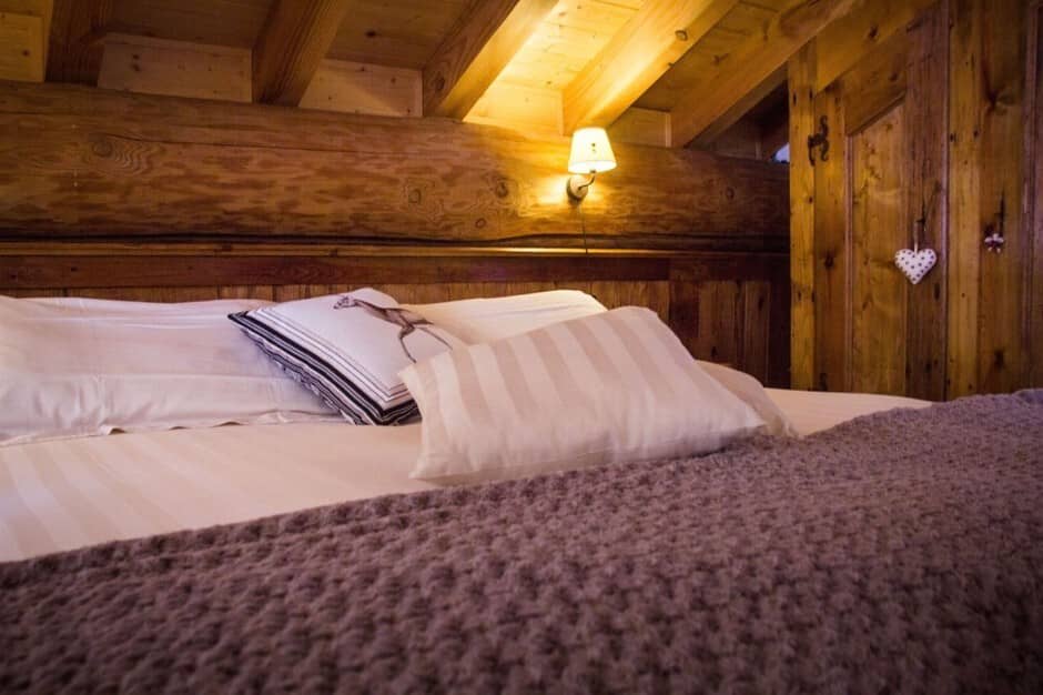 Bedroom with solid log walls and exposed timber ceiling beams