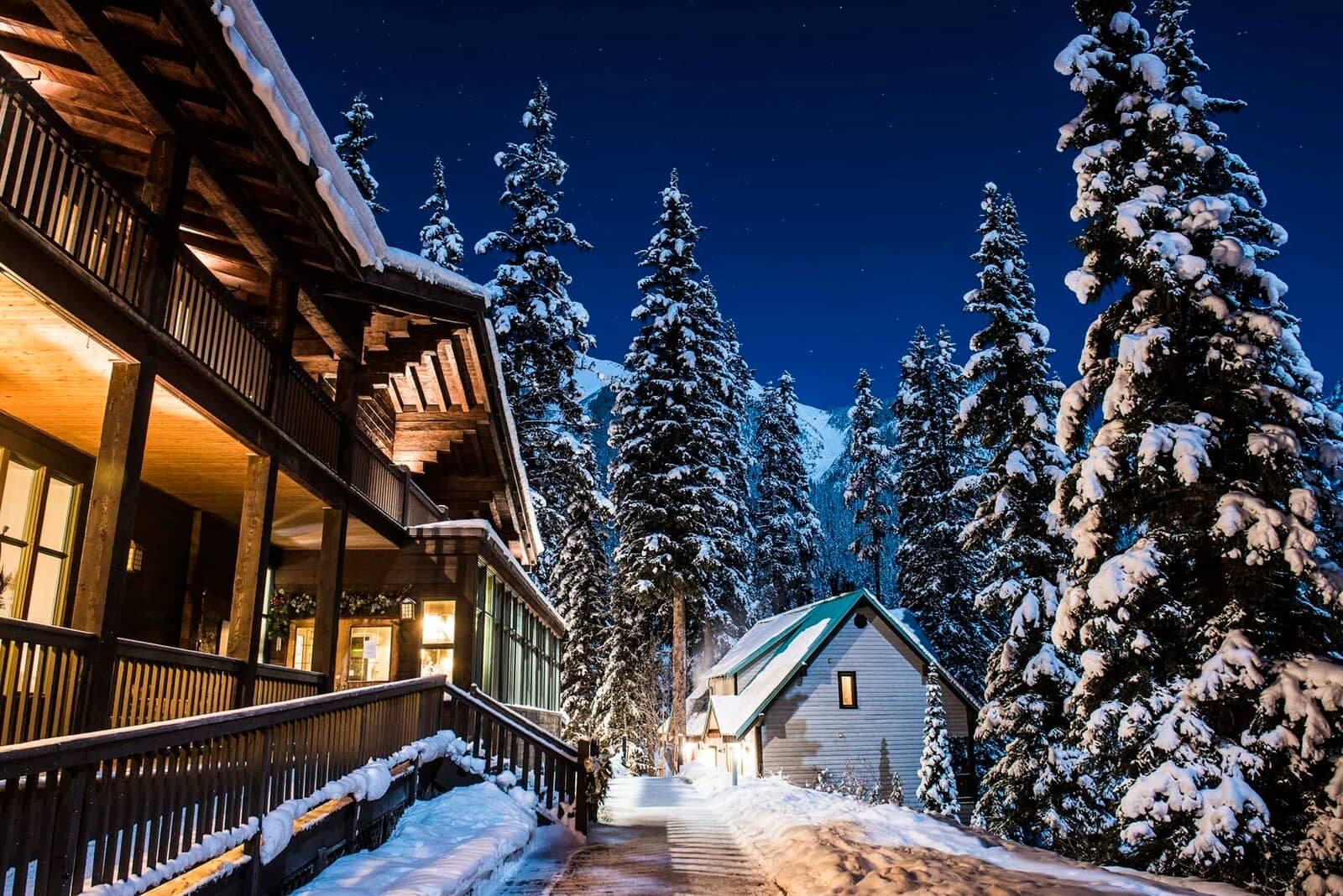 Chalet exterior at night with lighted walkway and mountain backdrop