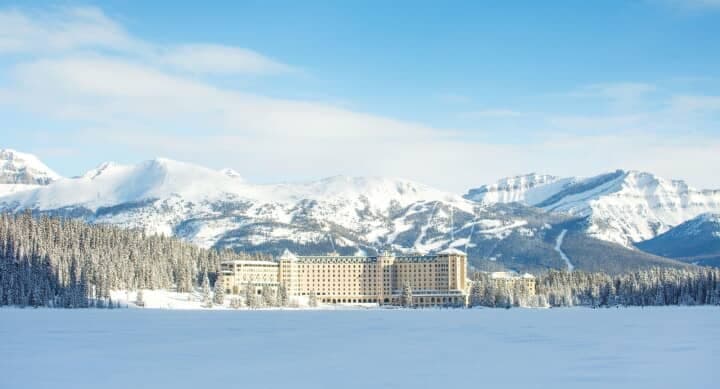 Resort exterior viewed from frozen Lake Louise with mountain backdrop