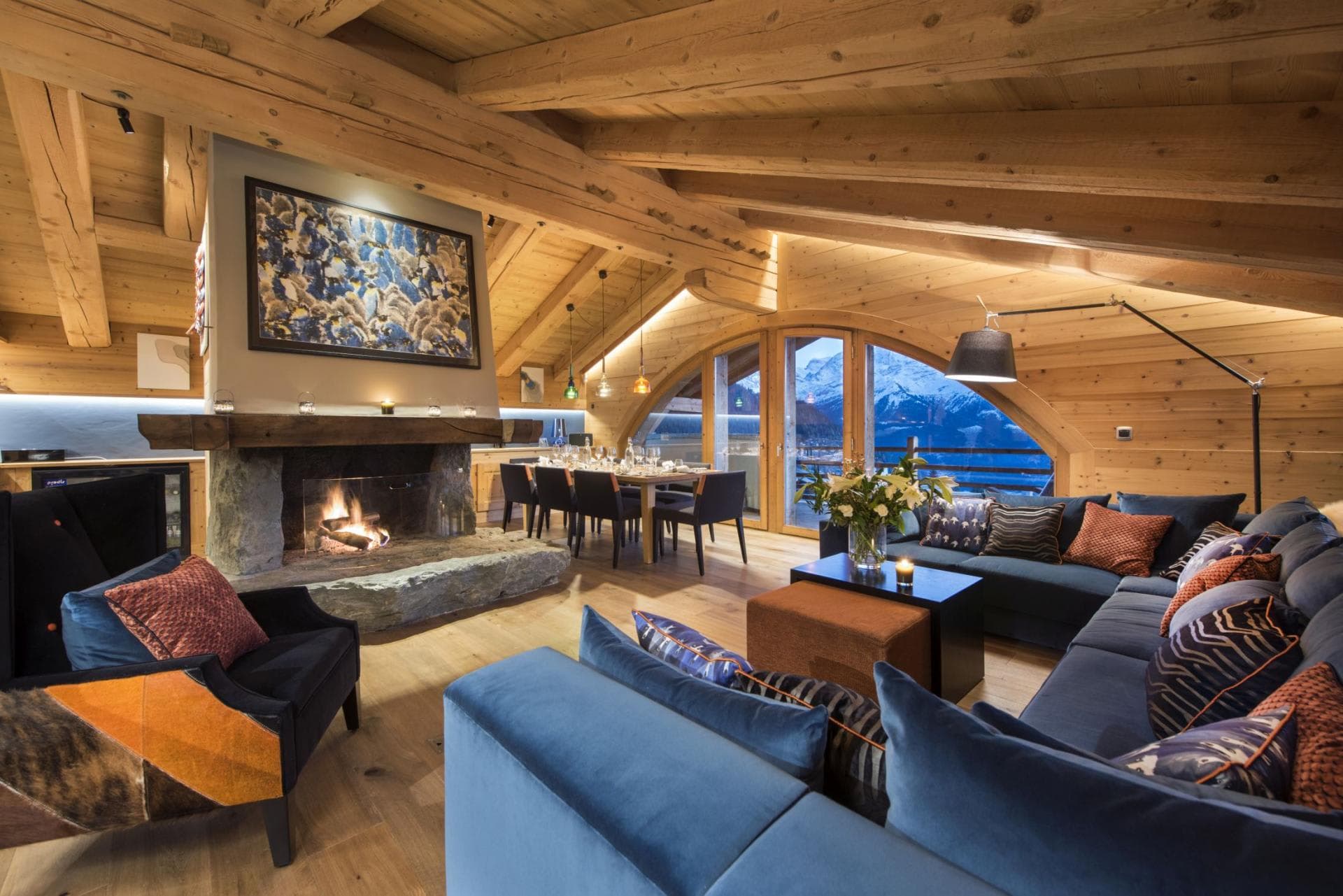 Open-plan living area with stone fireplace and mountain-view dining for 8
