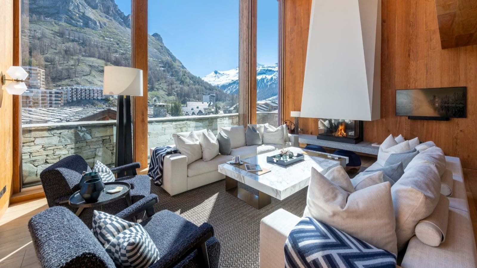 Living area with wood-burning fireplace and floor-to-ceiling mountain views