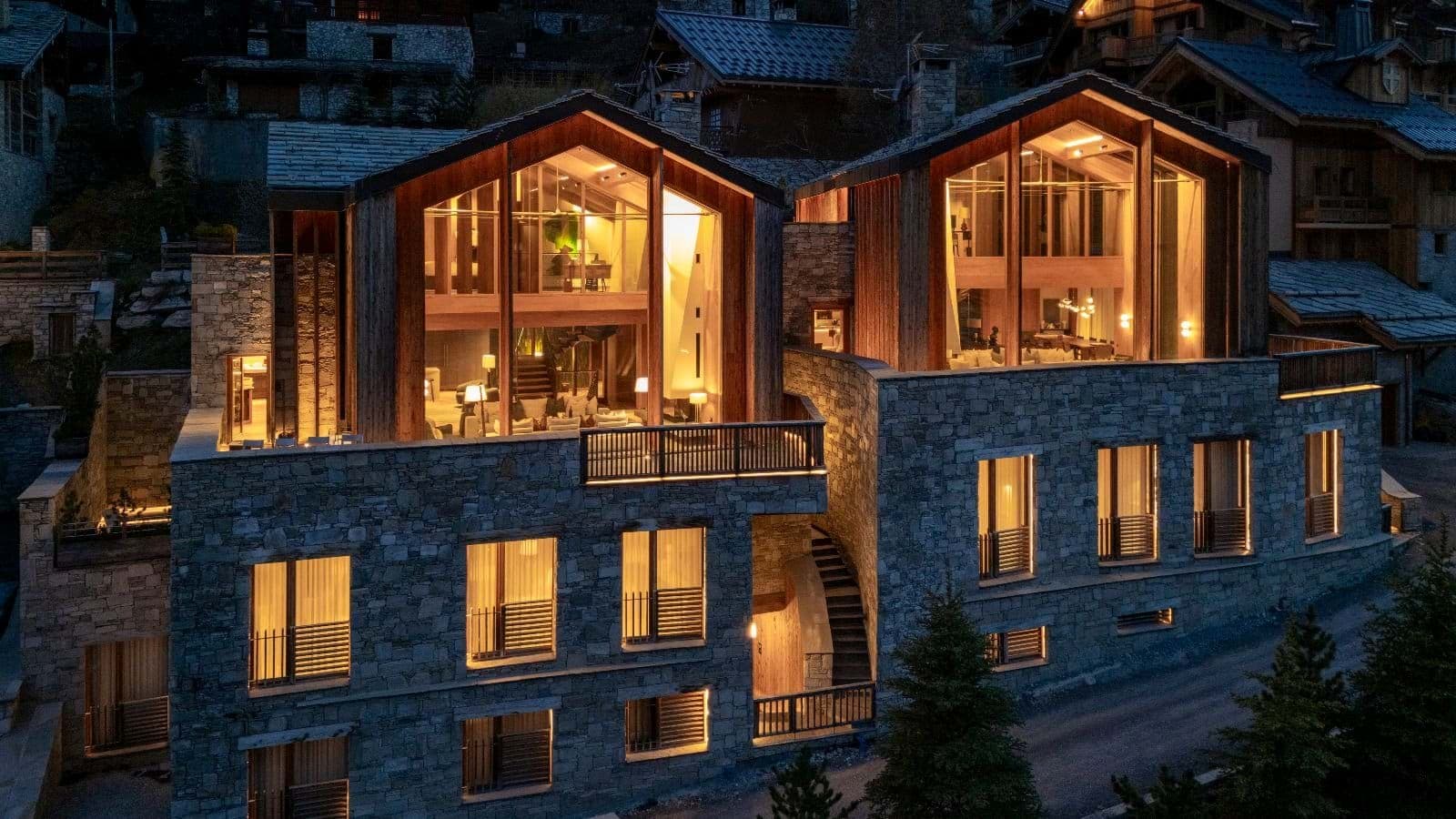 Stone-clad exterior featuring floor-to-ceiling windows and multiple private balconies