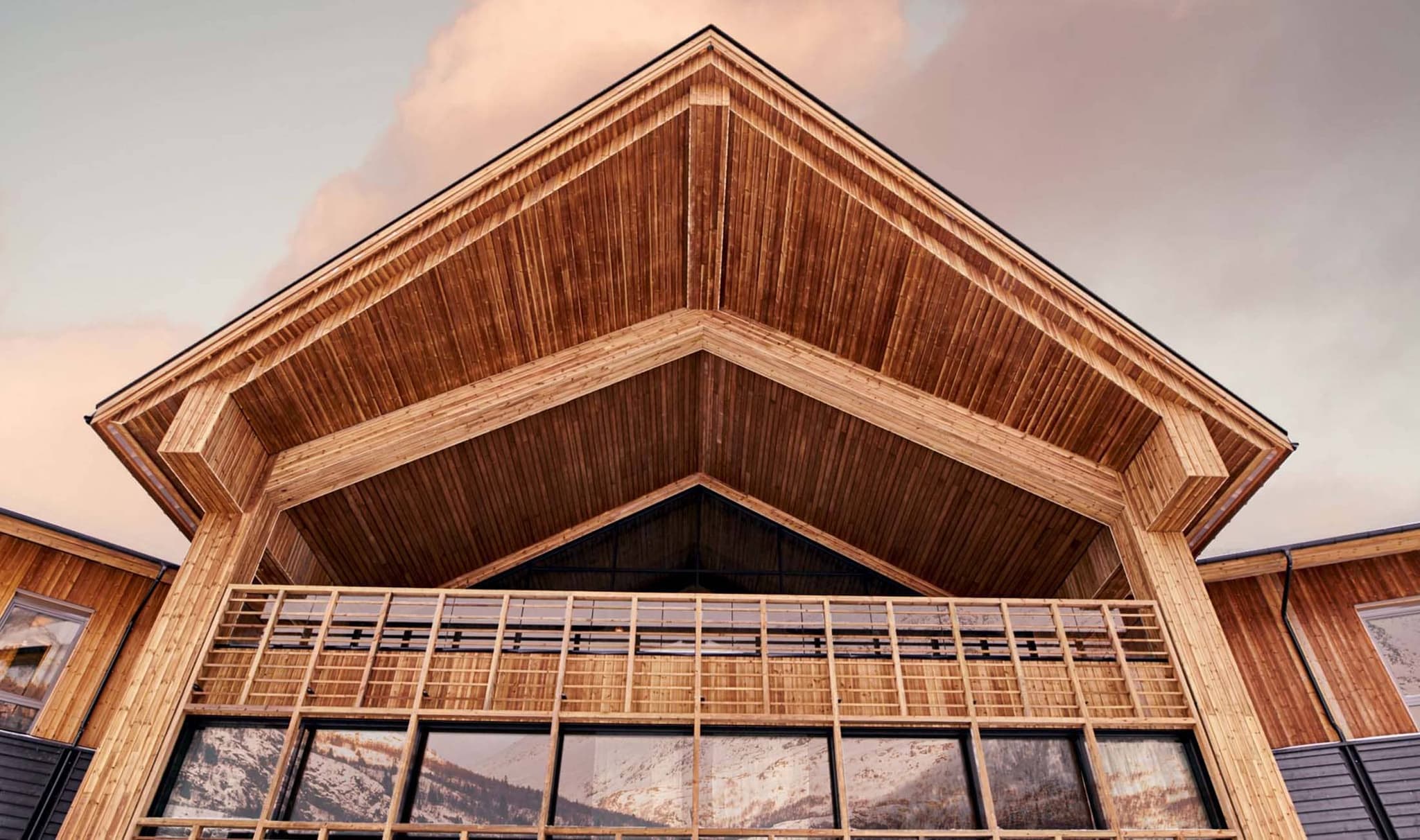 Chalet exterior featuring timber cladding and covered upper balcony with mountain reflections