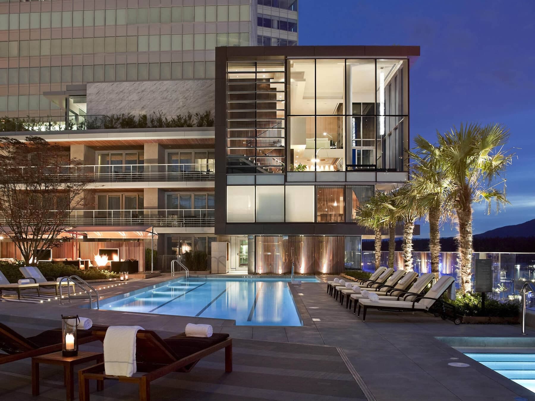 Rooftop lap pool with evening lighting and poolside fire pit