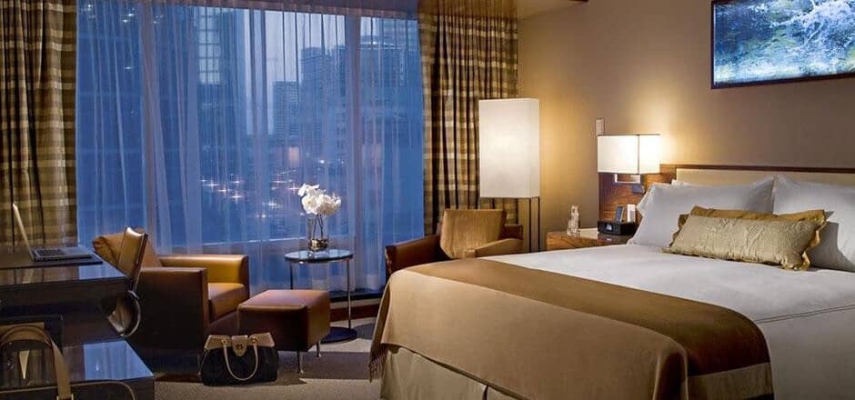 Guest suite with king bed, dedicated workspace, and city skyline views