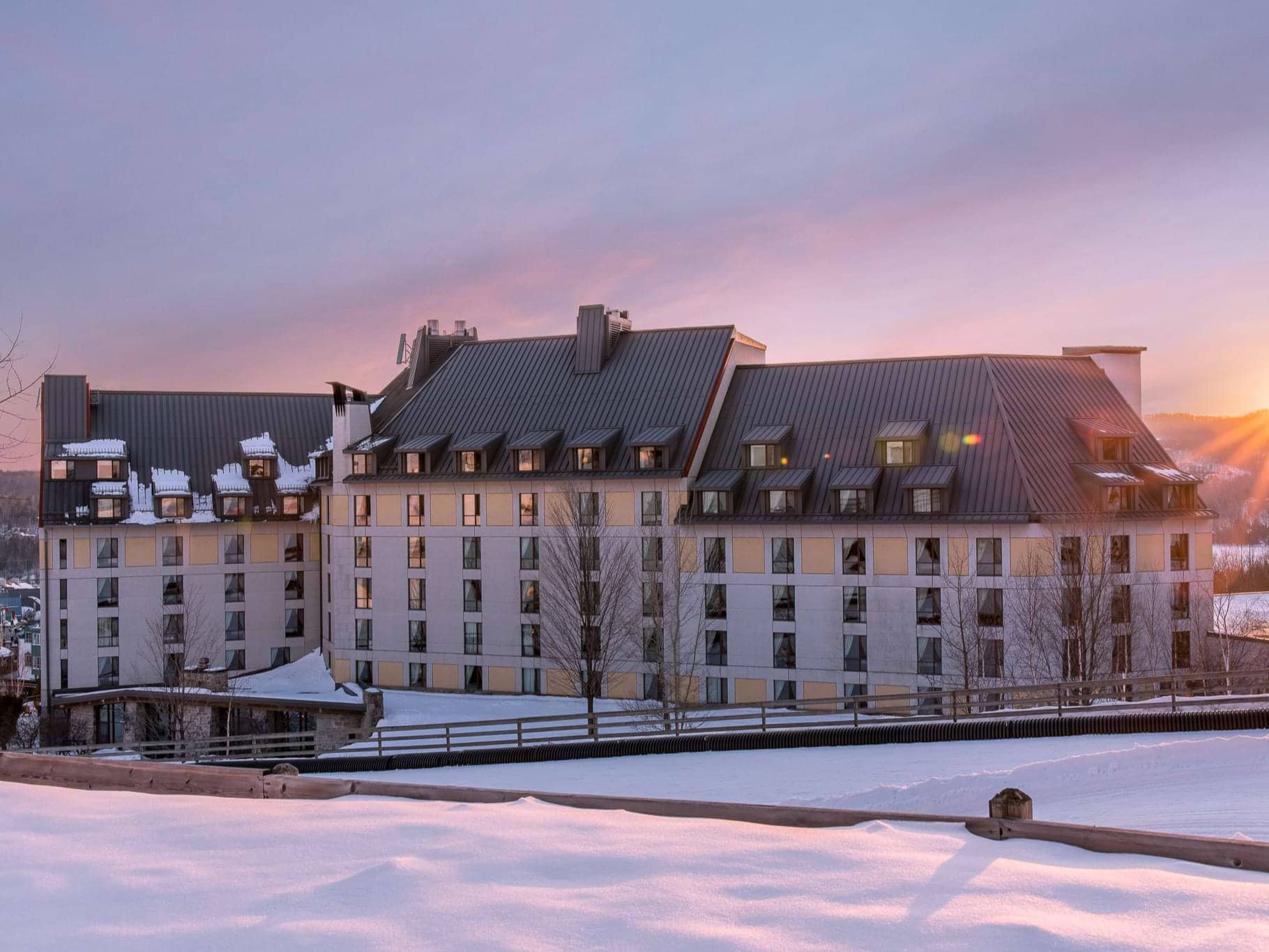 Lodge exterior at sunset with mountain views and snowy slope access