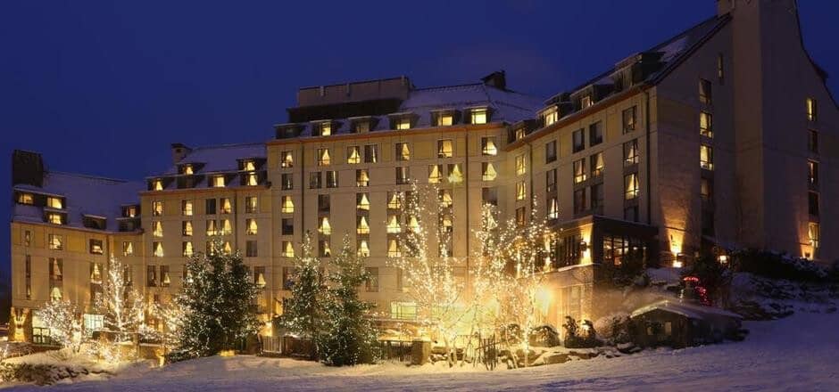 Main lodge exterior at night with snow and festive lighting