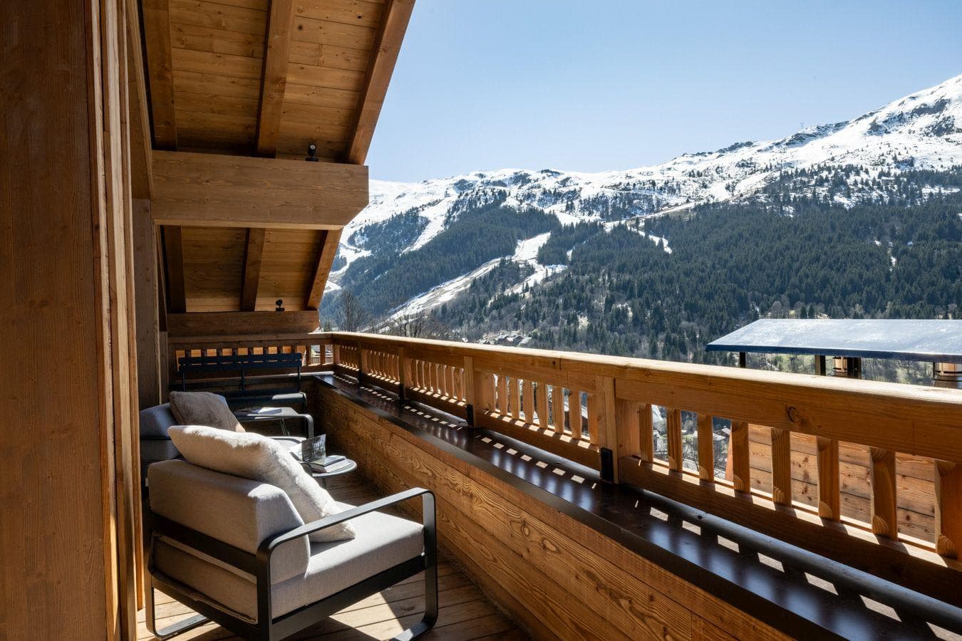 Covered timber balcony with armchairs and panoramic mountain views