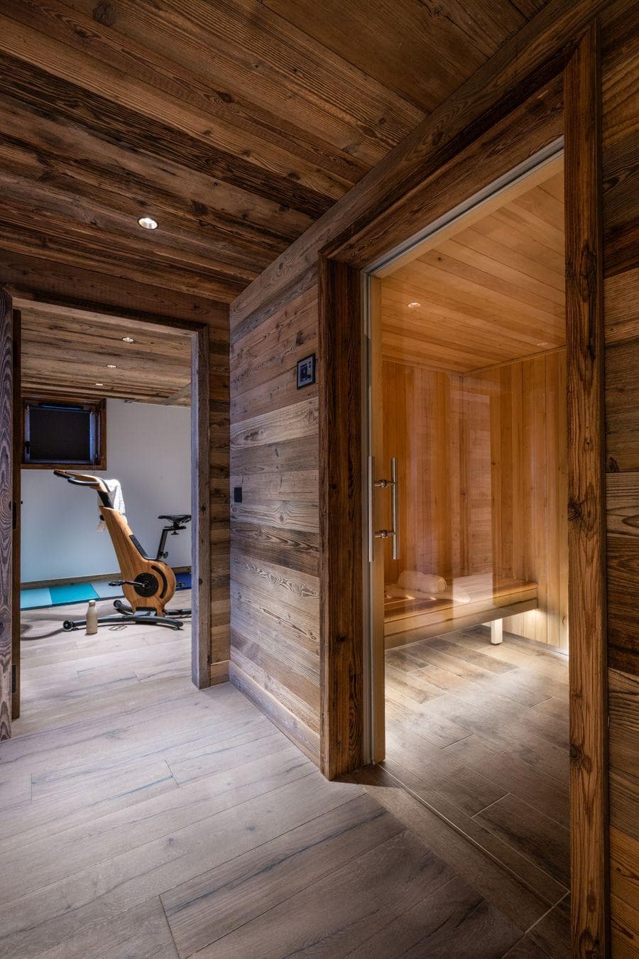 Private wellness area with wood-clad sauna and adjacent fitness room