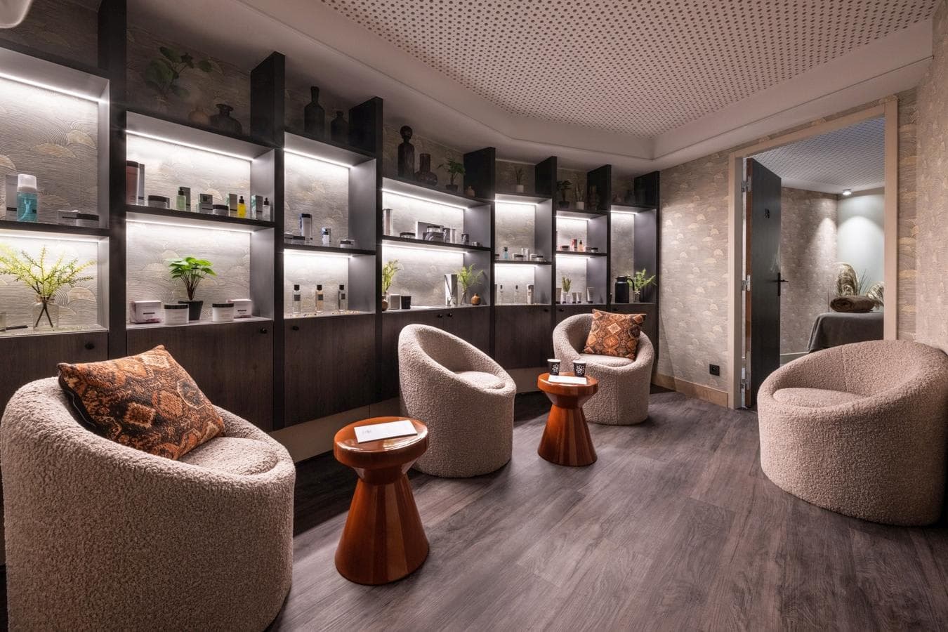 Spa lounge with bouclé armchairs and private treatment room beyond