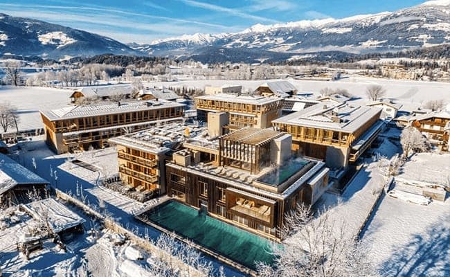 Aerial view of resort featuring heated outdoor infinity pool and mountain backdrop