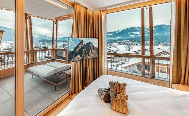 Primary bedroom with mountain-facing balcony and floor-to-ceiling windows