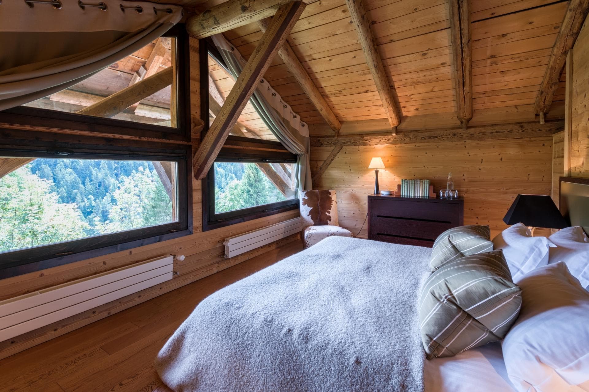 Loft bedroom with forest views and exposed timber beams