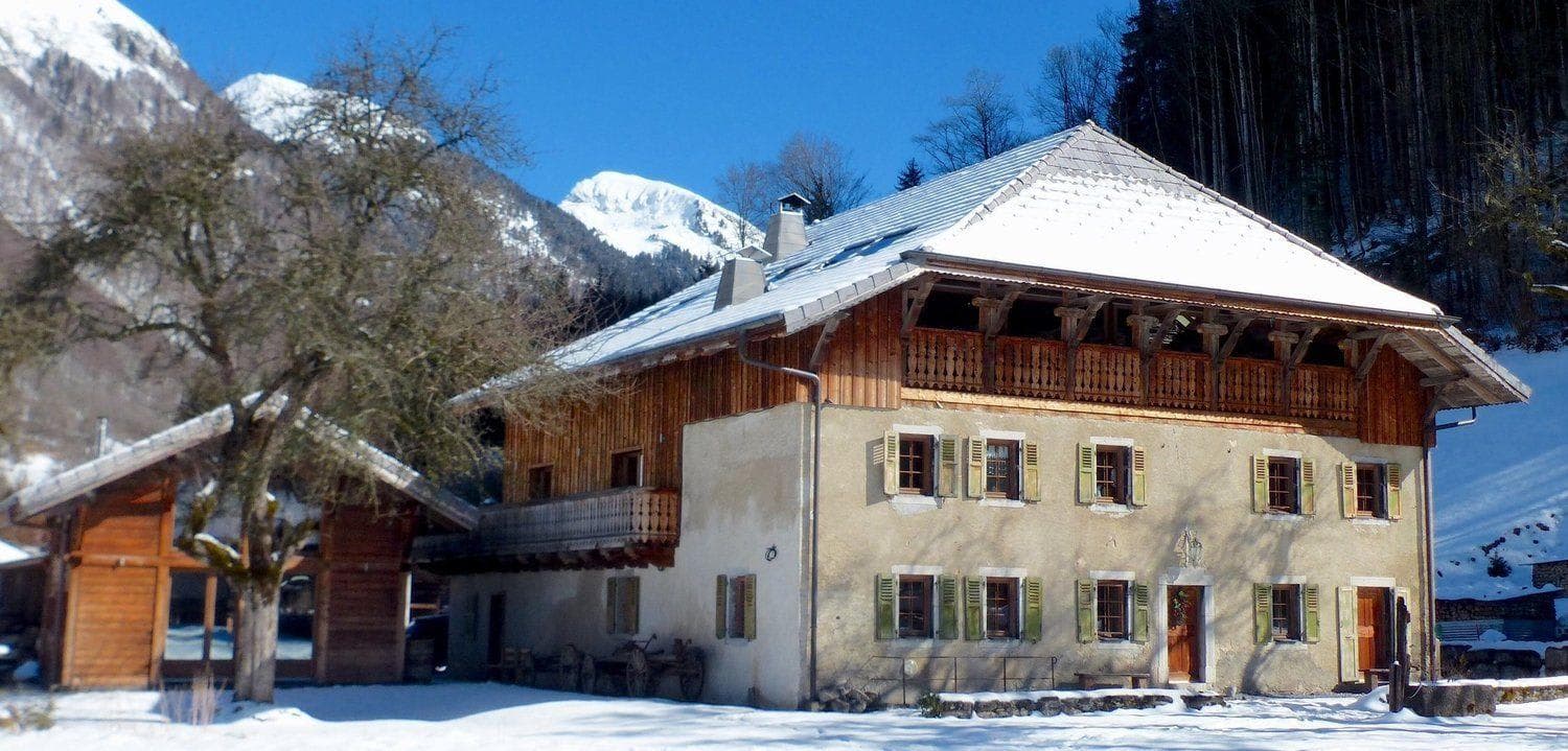 Traditional alpine chalet with original shutters and snowy mountain backdrop