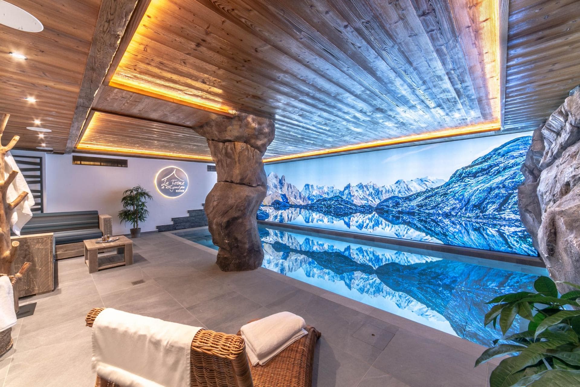 Indoor pool featuring panoramic mountain mural and lounge seating