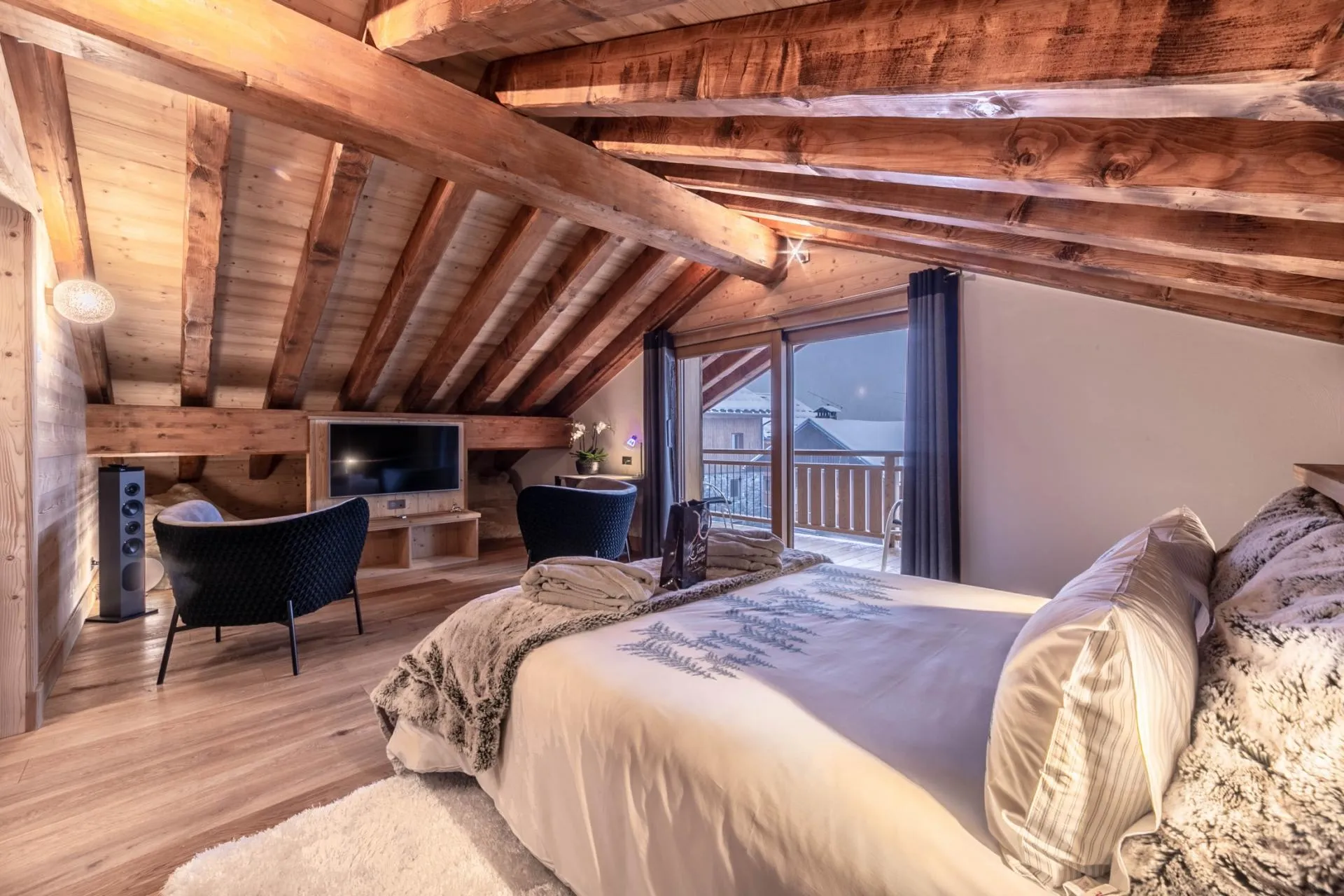 Bedroom beneath a pitched timber ceiling with balcony access