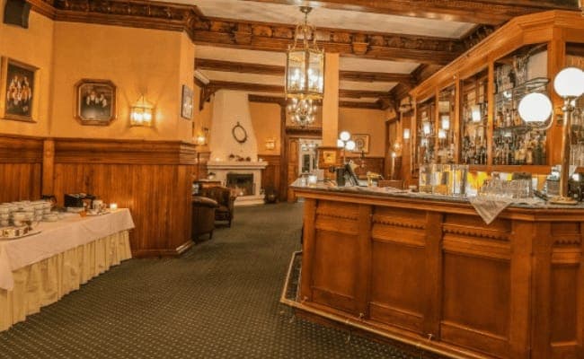 Wood-paneled lounge with full-service bar and wood-burning fireplace