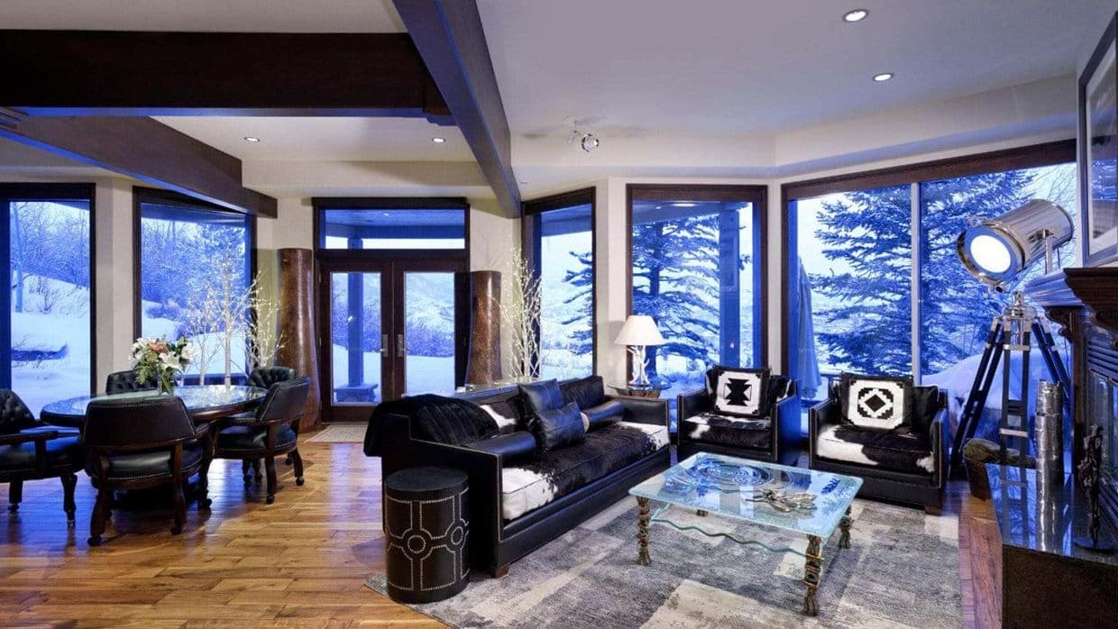 Open living area with fireplace and floor-to-ceiling windows; snowy mountain views