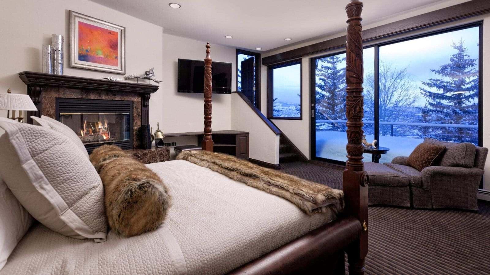 Primary bedroom with king four-poster bed, fireplace, and snowy mountain views