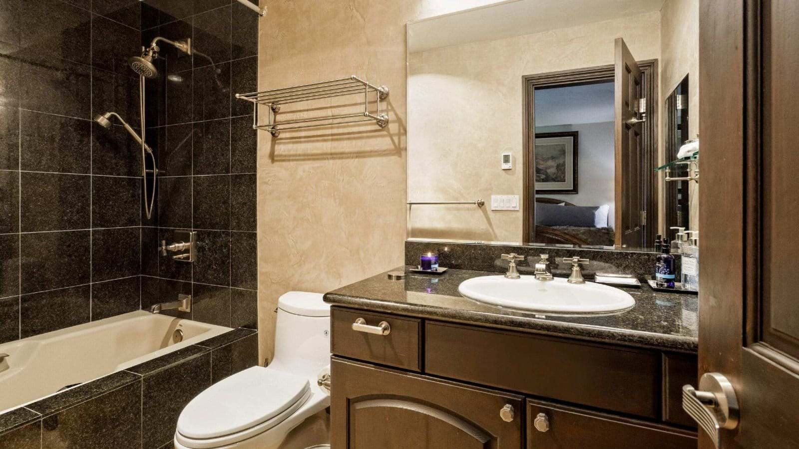 Full bathroom with dark granite vanity and shower-tub combo