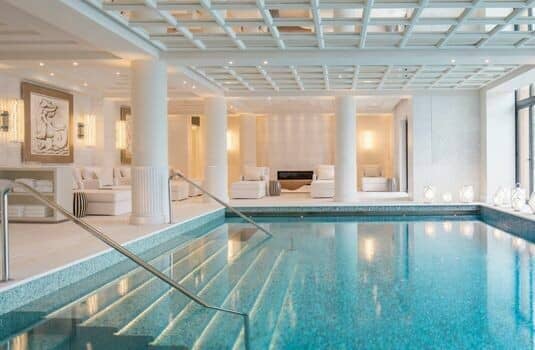 Indoor heated pool with walk-in steps and fireplace lounge